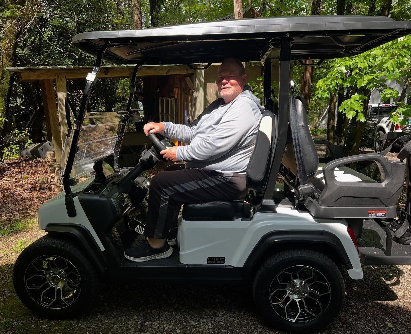A man is sitting in a white golf cart.