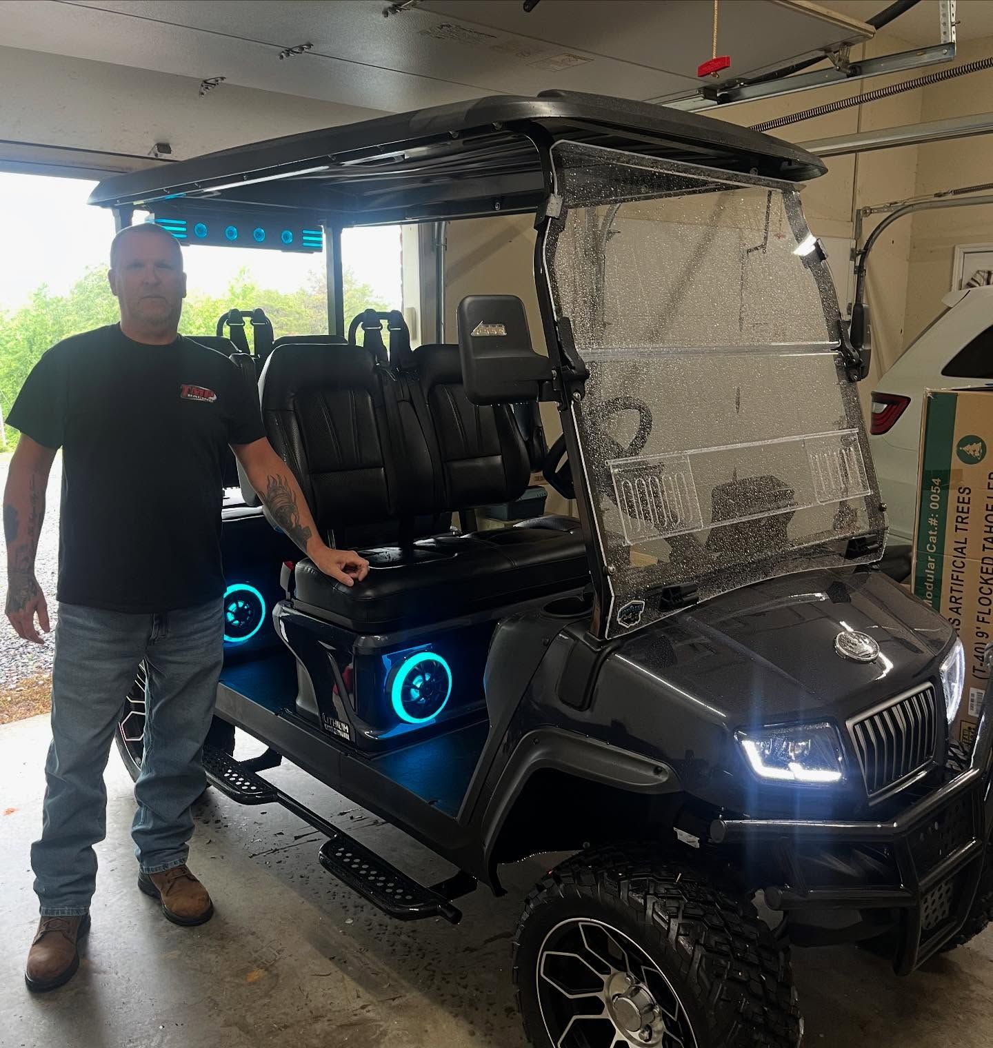 A man is standing next to a golf cart in a garage