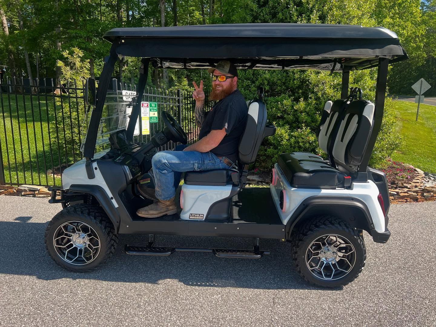 A man is sitting in a golf cart on the side of the road.
