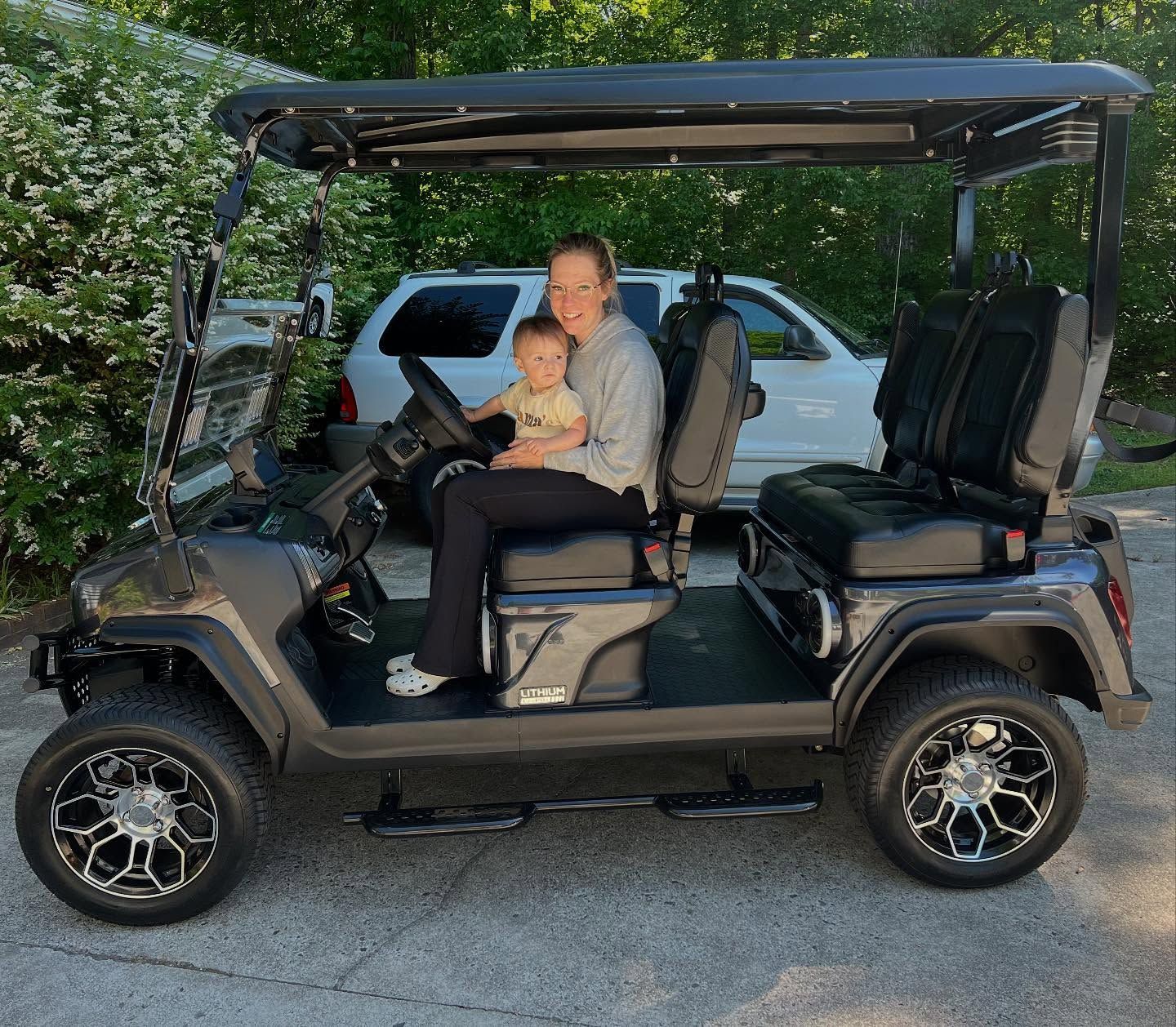 A woman and a child are sitting in a golf cart.