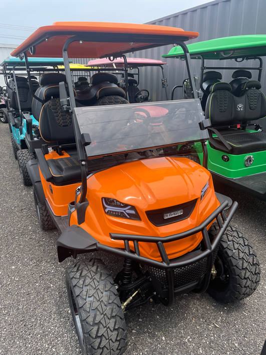 A row of golf carts are parked in a parking lot.