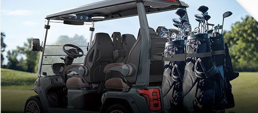 A golf cart filled with golf clubs is parked on a golf course.