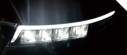A close up of a car headlight in the dark.