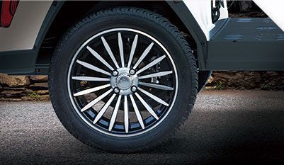 A close up of a golf cart wheel on a road.