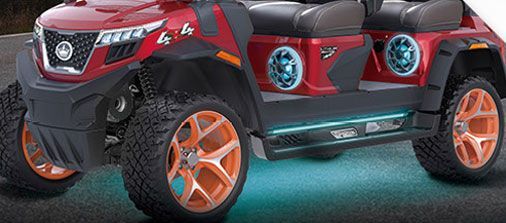 A red golf cart with orange wheels is parked on the side of the road.