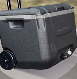 A black cooler with wheels and handles is sitting on a table.
