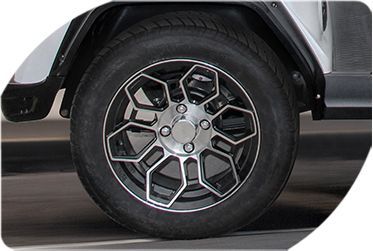 A close-up of a golf cart wheel on a road.