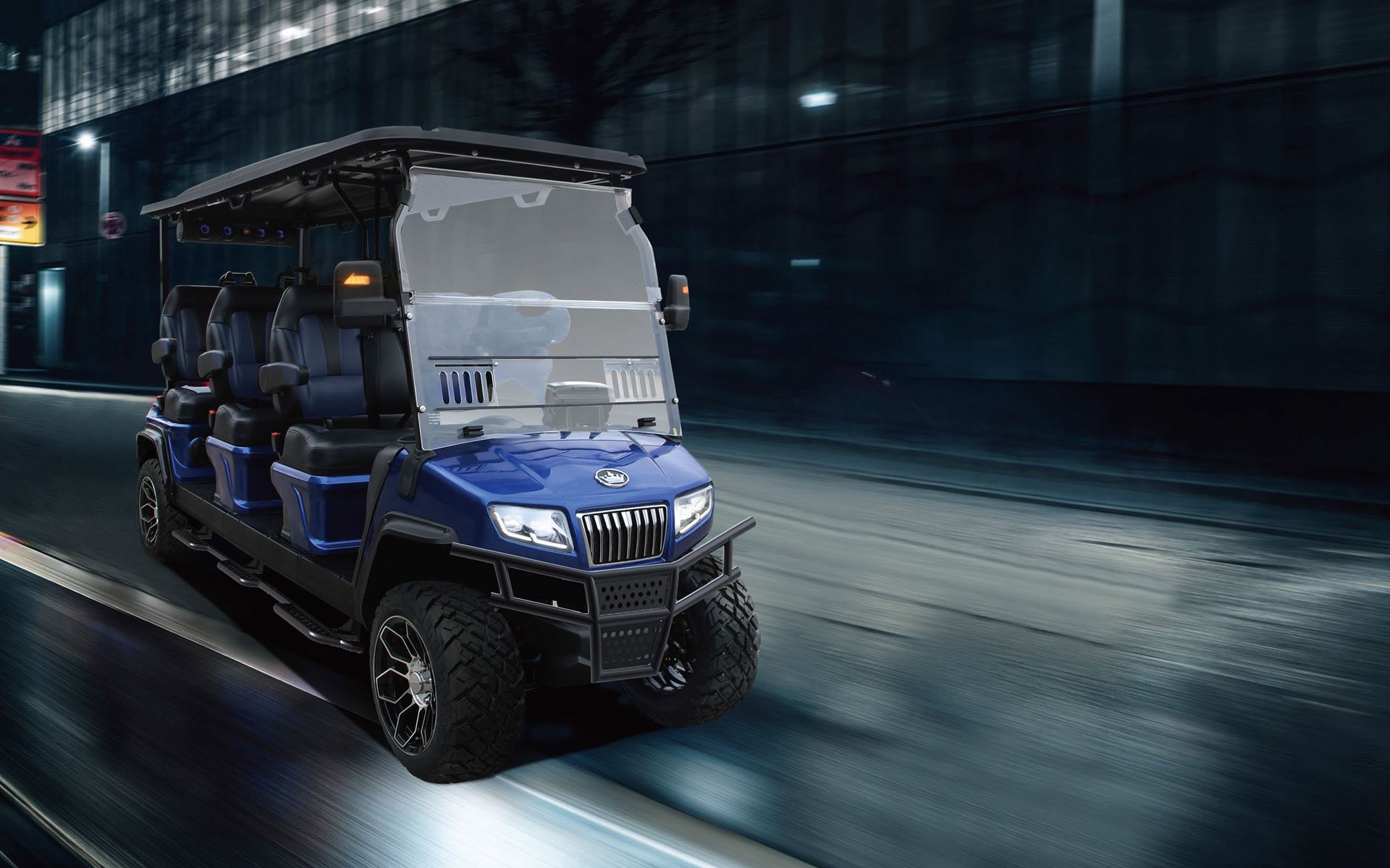 A blue golf cart is driving down a street at night.