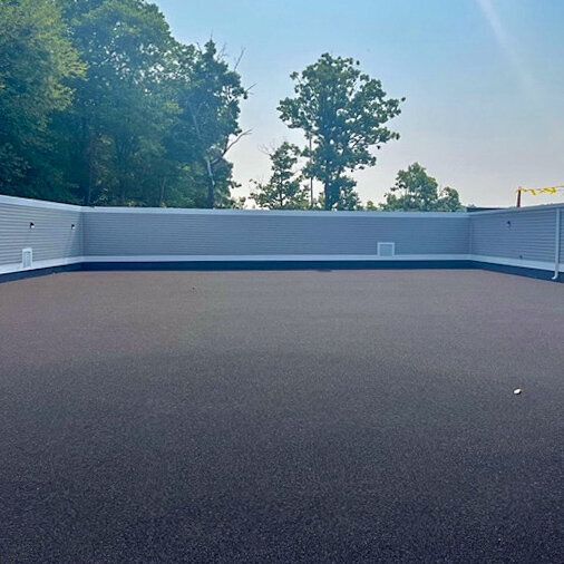 An empty rooftop with a fence and trees in the background.