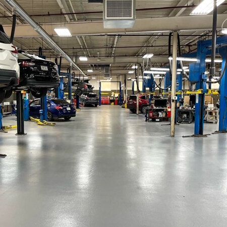 A large garage filled with lots of cars on lifts.