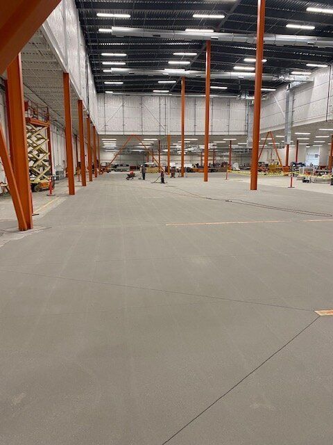 A large empty brewery with orange poles and a concrete floor