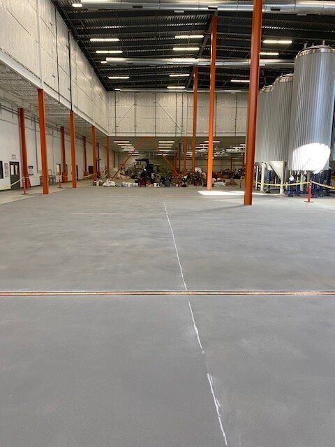 A large brewery with a concrete floor and a lot of tanks