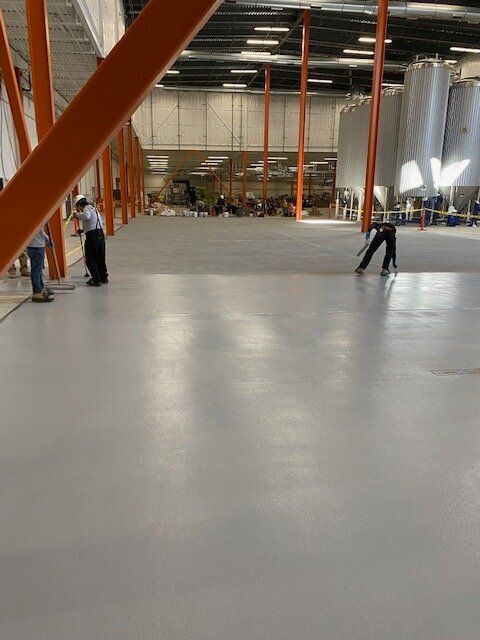 A group of people are standing in a large brewery.