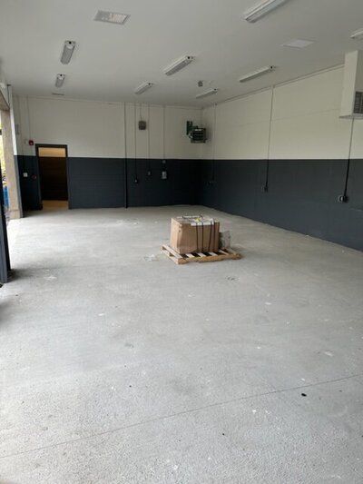 A large empty room with a pallet of boxes on the floor.