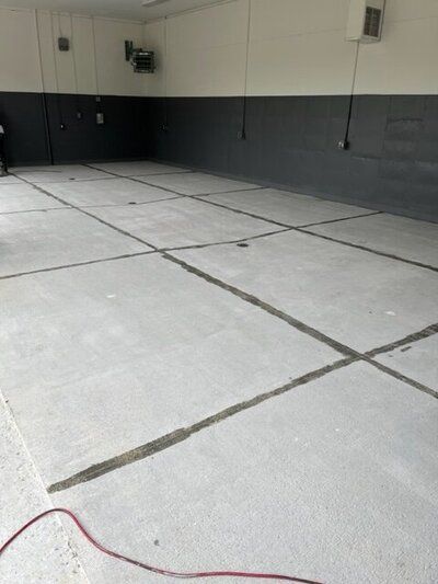 A large empty room with a concrete floor and a red cord.