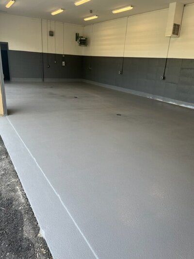 A large empty golf facility with a gray floor and white walls.