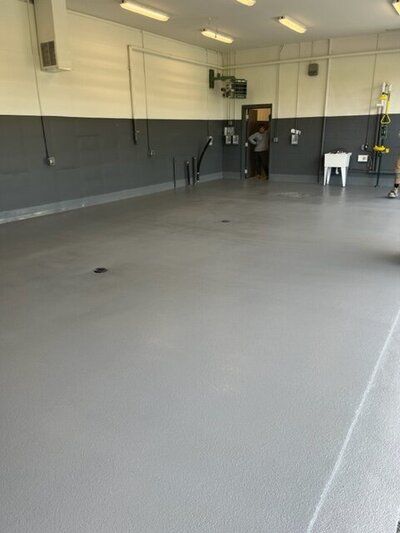 A large empty golf facility with a gray floor and white walls.