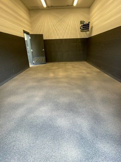 A large empty room with a gray floor and black walls.