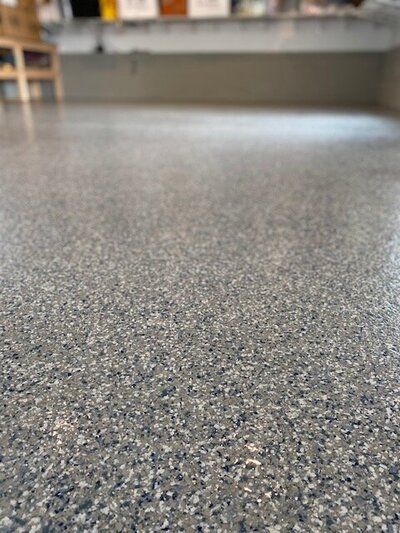 A close up of a gray floor with a shelf in the background.