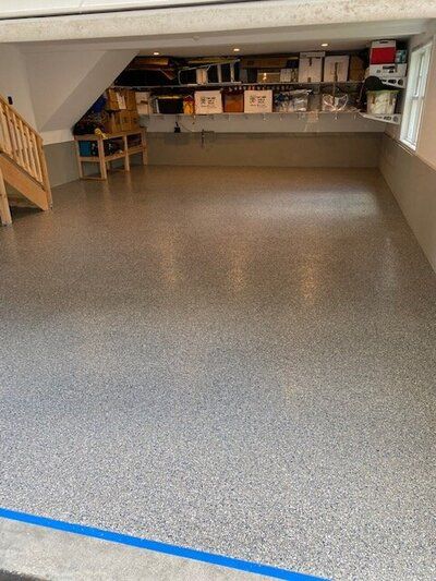 A garage with a gray floor and a staircase.