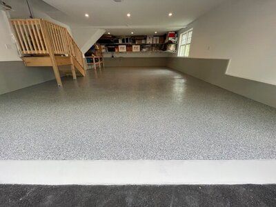 A garage with a staircase and a gray floor.