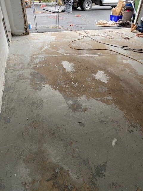 A dirty concrete floor in a garage with a vacuum cleaner.