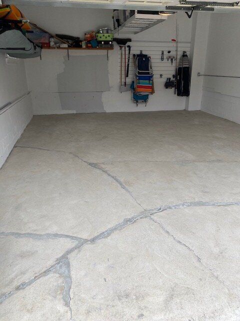An empty garage with a cracked concrete floor