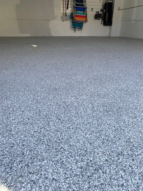 A garage with a gray carpeted floor and a white wall.