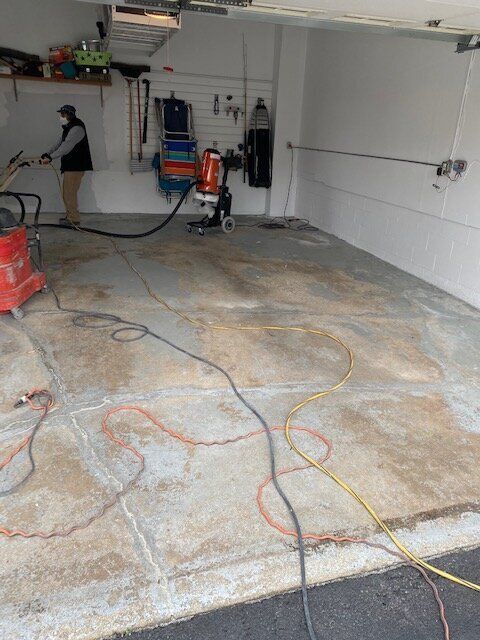 A man is cleaning the floor of a garage with a vacuum cleaner.