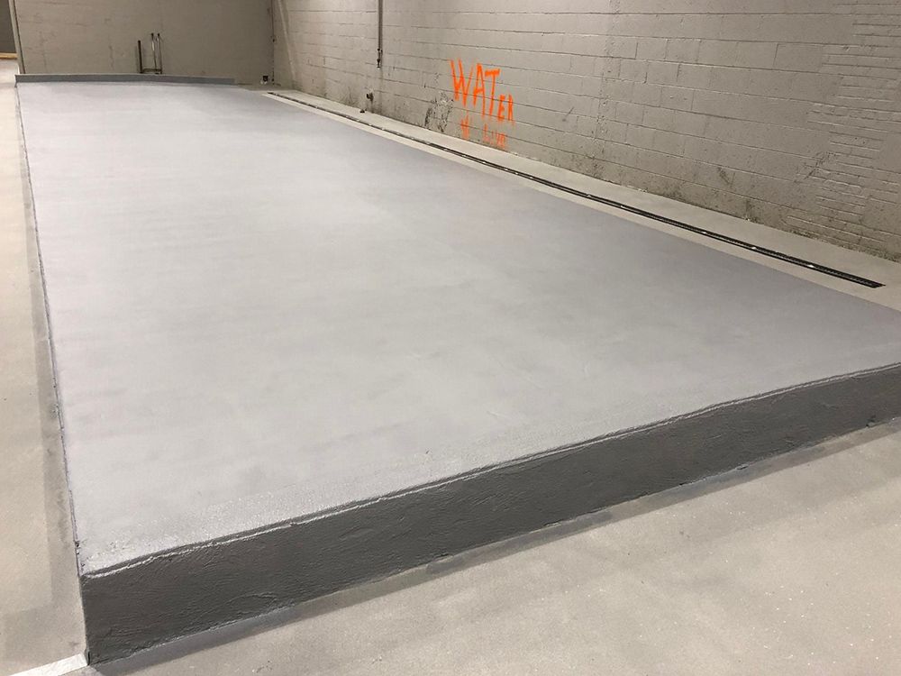 A large concrete slab is sitting in a room next to a brick wall.
