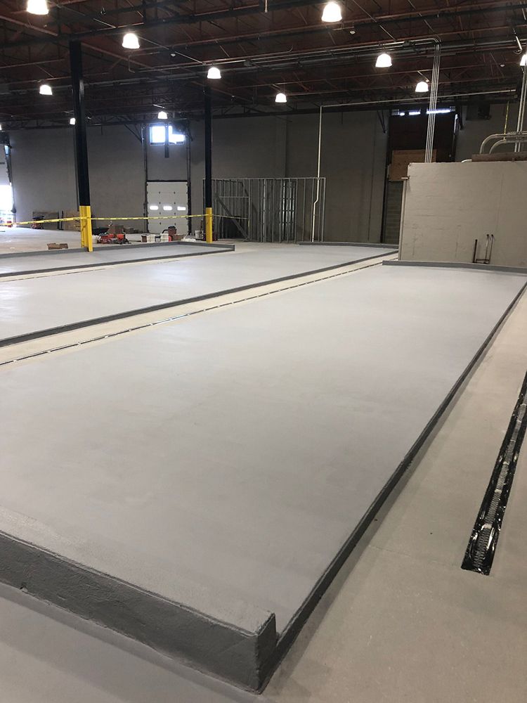 A large empty brewery with a white floor and a yellow barrier.