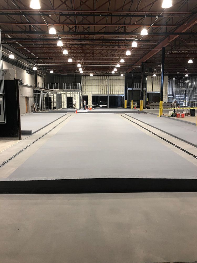 A large brewery with a concrete floor and a lot of lights on the ceiling.