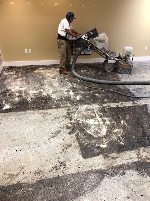 A man is grinding a concrete floor with a machine.
