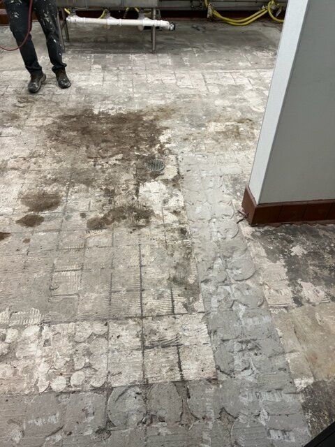 A person is standing on a tiled floor in a room.