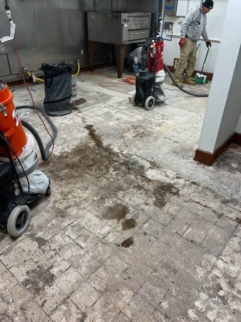 A man is cleaning a dirty floor with a vacuum cleaner.