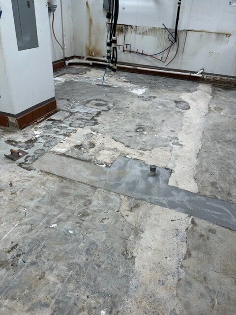 A room with a concrete floor and a white wall