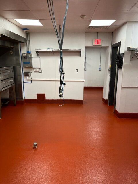 An empty kitchen with a red floor and a red exit sign
