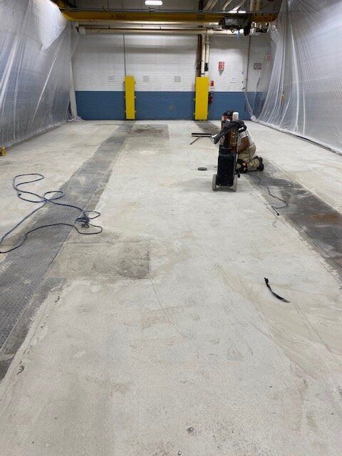 A man is working on a concrete floor in a manufacturing facility