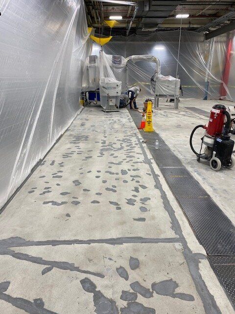 A man is working on a concrete floor in a manufacturing facility