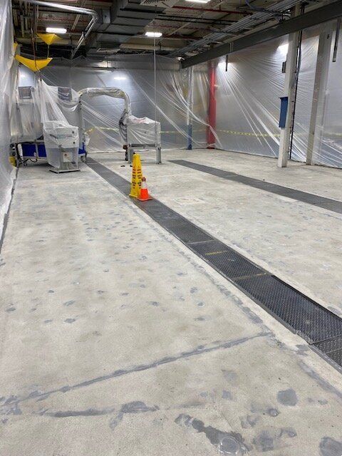 A large room with a concrete floor and a yellow cone on the floor.