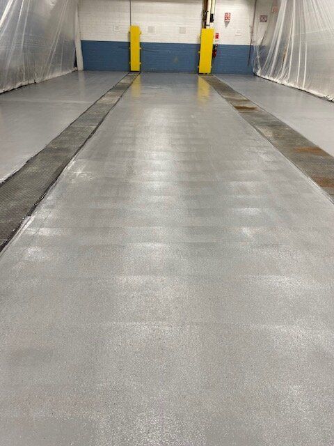 A warehouse with a gray floor and yellow poles