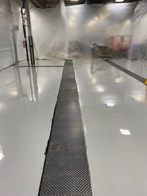 A large room with a concrete floor and a metal drain.