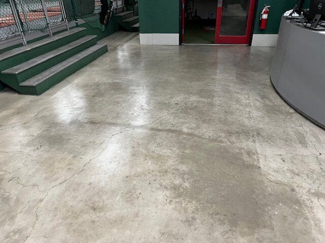 A concrete floor in a room with stairs and a fire extinguisher.