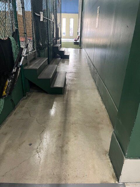 A hallway with stairs and a green wall in a building.