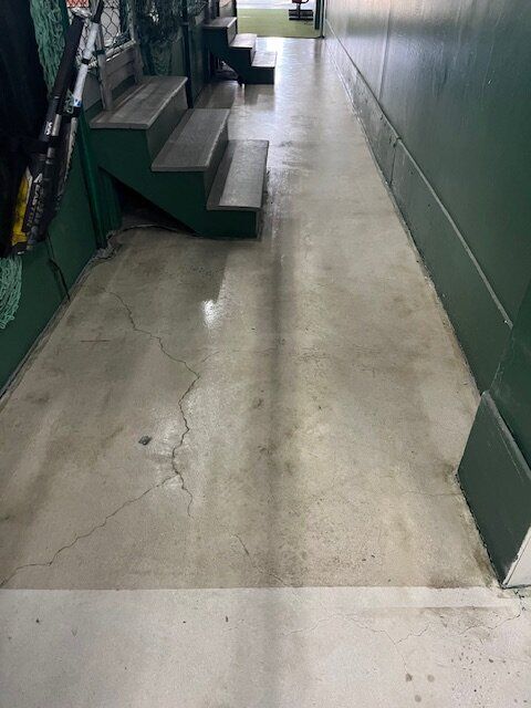 A long hallway with stairs and a green wall.