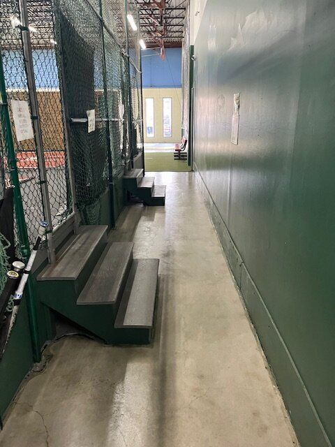 A long hallway with stairs and a green wall.