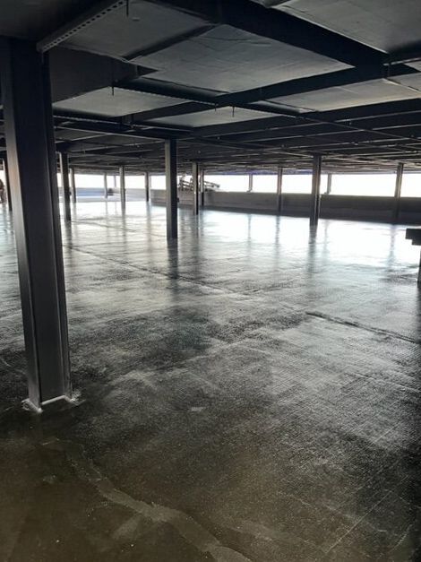 An empty parking garage with a concrete floor and columns.