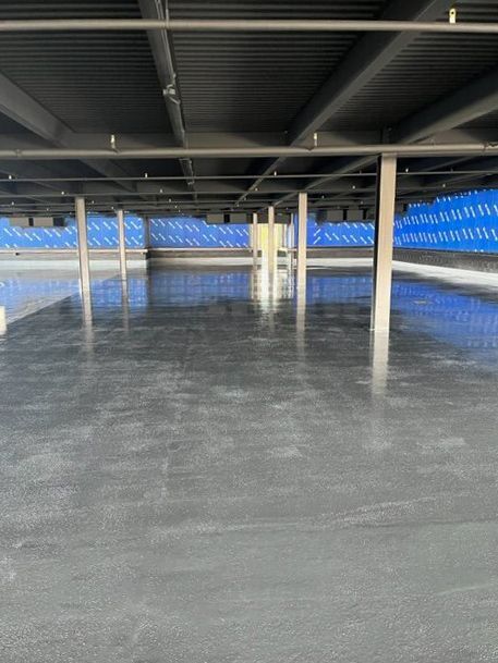 A large empty parking garage with a concrete floor and columns.