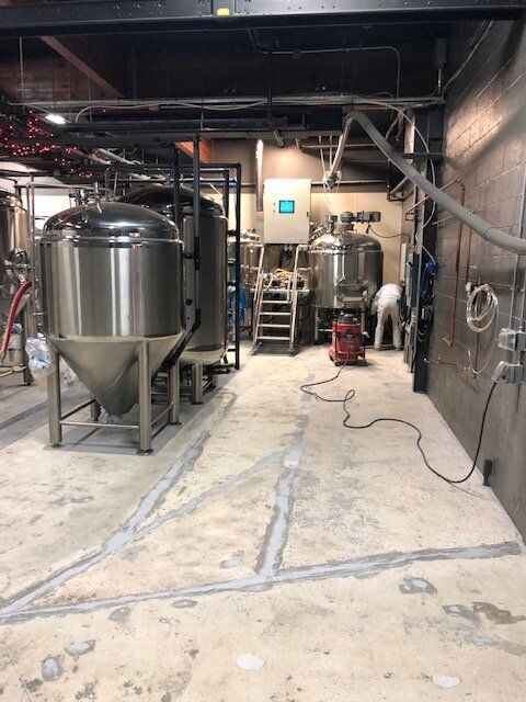 A factory with a lot of stainless steel tanks and a vacuum cleaner.