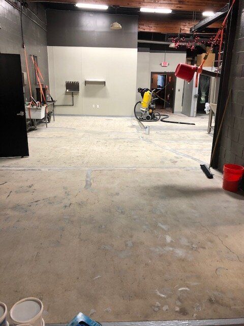 An empty room with a broom and buckets on the floor